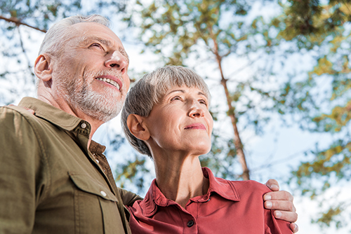 Elderly couple looking away from the camera and smiling outside