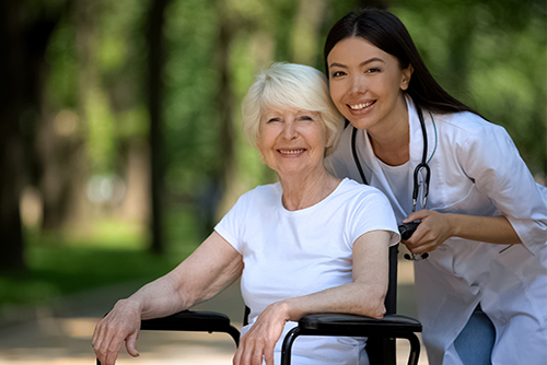 Nurse pushing smiling patient in wheelchair outside