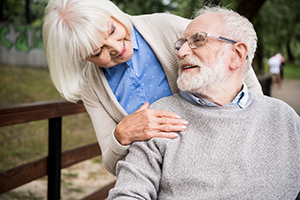 Wife standing behind husband in wheelchair smiling at each other